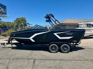 Modern black and white boat on trailer at marina under clear blue sky.