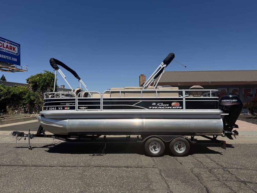 Pontoon boat with outboard motor and fishing features on trailer.