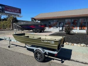 Lowe 1040 fishing boat on trailer outside surf shop with mural background.