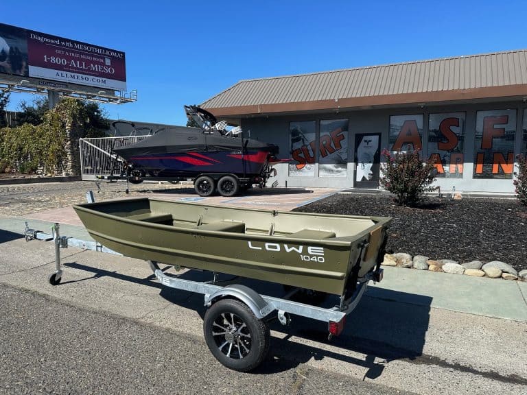 Lowe 1040 fishing boat on trailer outside surf shop with mural background.