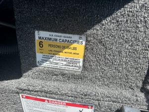 U.S. Coast Guard maximum boat capacity label with weight and person limits.