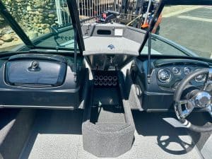 Boat dashboard with steering wheel, gauges, and control panel for marine navigation.