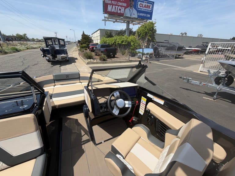 Opti marine boat cockpit with beige seating and steering wheel.