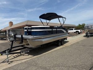 Pontoon boat on trailer with canopy, ready for water, at marina.