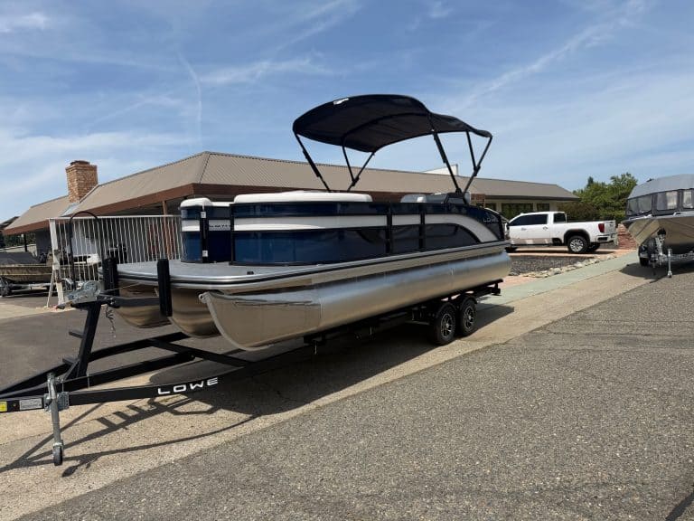 Pontoon boat on trailer with canopy, ready for water, at marina.