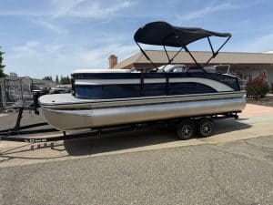 Modern pontoon boat with canopy on trailer, ideal for leisure and fishing.