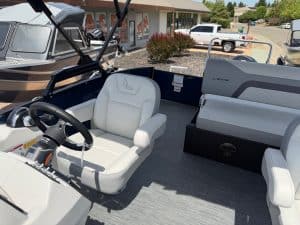 Boat cockpit with white seating and steering wheel at a marina.