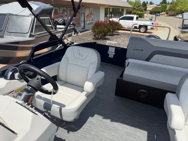 Boat cockpit with white seating and steering wheel at a marina.