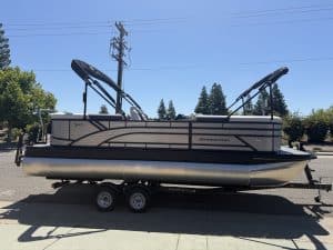 Modern Renegade pontoon boat with wakeboard towers on trailer, ideal for water sports and leisure.