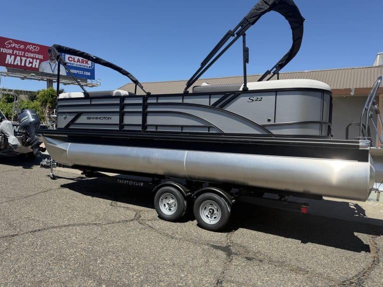 Modern pontoon boat with canopy and dual-axle trailer for outdoor water activities.
