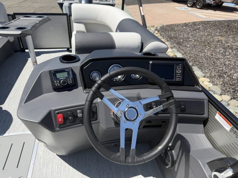 Boat dashboard with steering wheel, gauges, and electronic navigation system for marine vessels.