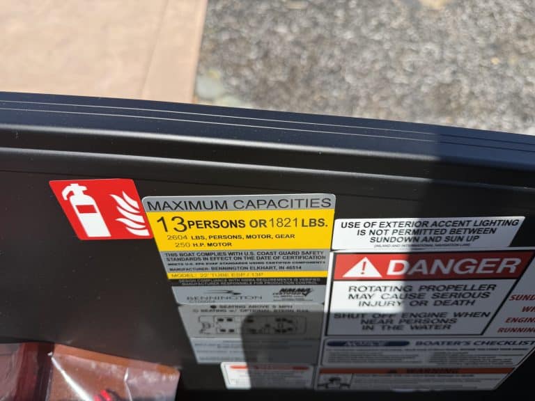 Close-up of Bennington M 23 boat with 250HP outboard motor and safety labels.