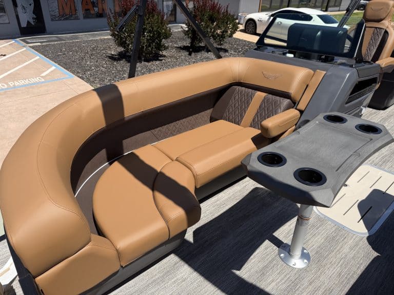 Luxury tan and black pontoon boat seating with cup holders and table.