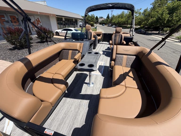 Bennington M 23 pontoon boat with tan seating and black canopy.