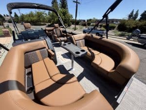 Luxury pontoon boat interior with tan seating and steering console.