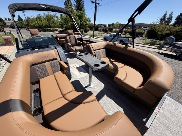 Luxury pontoon boat interior with tan seating and steering console.