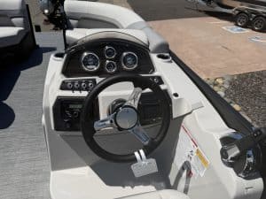 Boat dashboard with steering wheel, gauges, and control panel for navigation and operation.