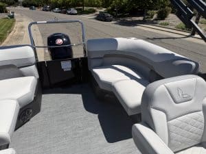 Pontoon boat with comfortable white cushioned seats and steering console.