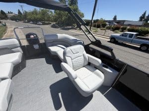 Pontoon boat interior with plush white seats, steering console, and panoramic view for leisure boati.