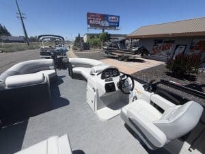 Boat cockpit with white seating and steering console at a marina dealership.