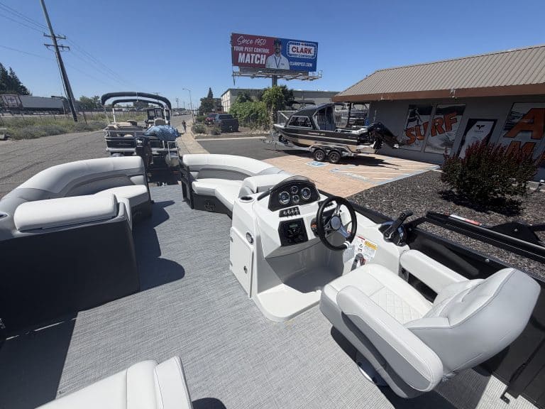 Boat cockpit with white seating and steering console at a marina dealership.