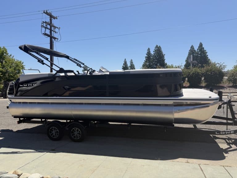 Luxury pontoon boat with sleek black and silver design on trailer for sale.