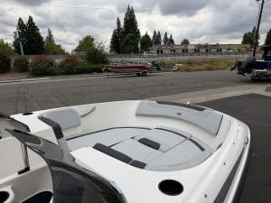 Boat with seating and outboard motor, parked outdoors on a cloudy day.