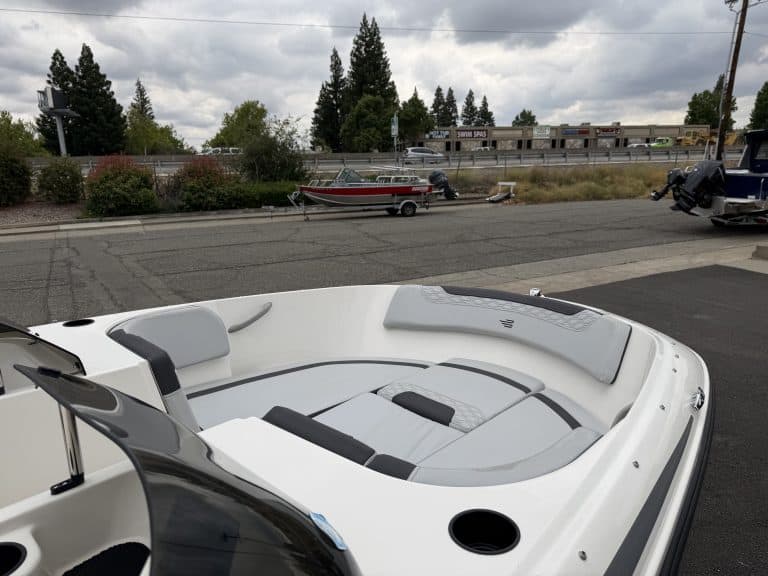 Boat with seating and outboard motor, parked outdoors on a cloudy day.