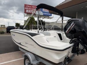 Boat with Mercury outboard motor at a dealership lot.