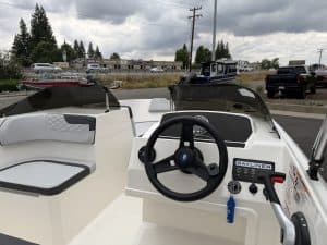 Boat steering console with navigation controls and seating area.