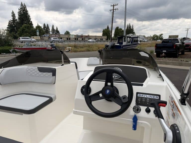 Boat steering console with navigation controls and seating area.