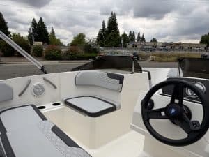 Boat cockpit with steering wheel and seating area.