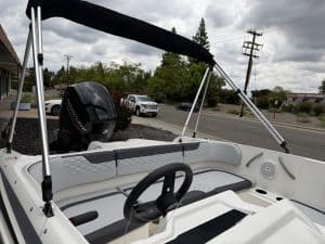 Boat interior with steering wheel and seating, outdoor setting.