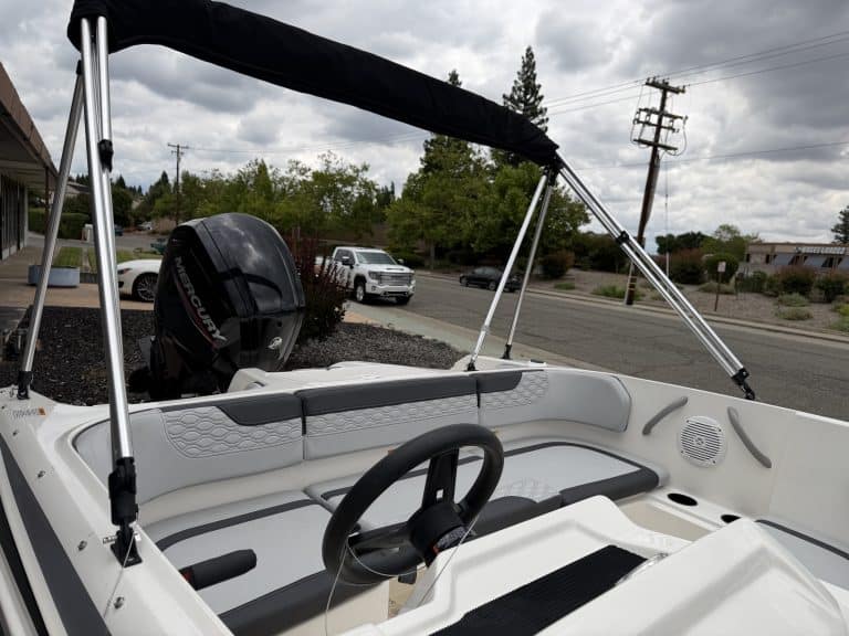 Boat interior with steering wheel and seating, outdoor setting.
