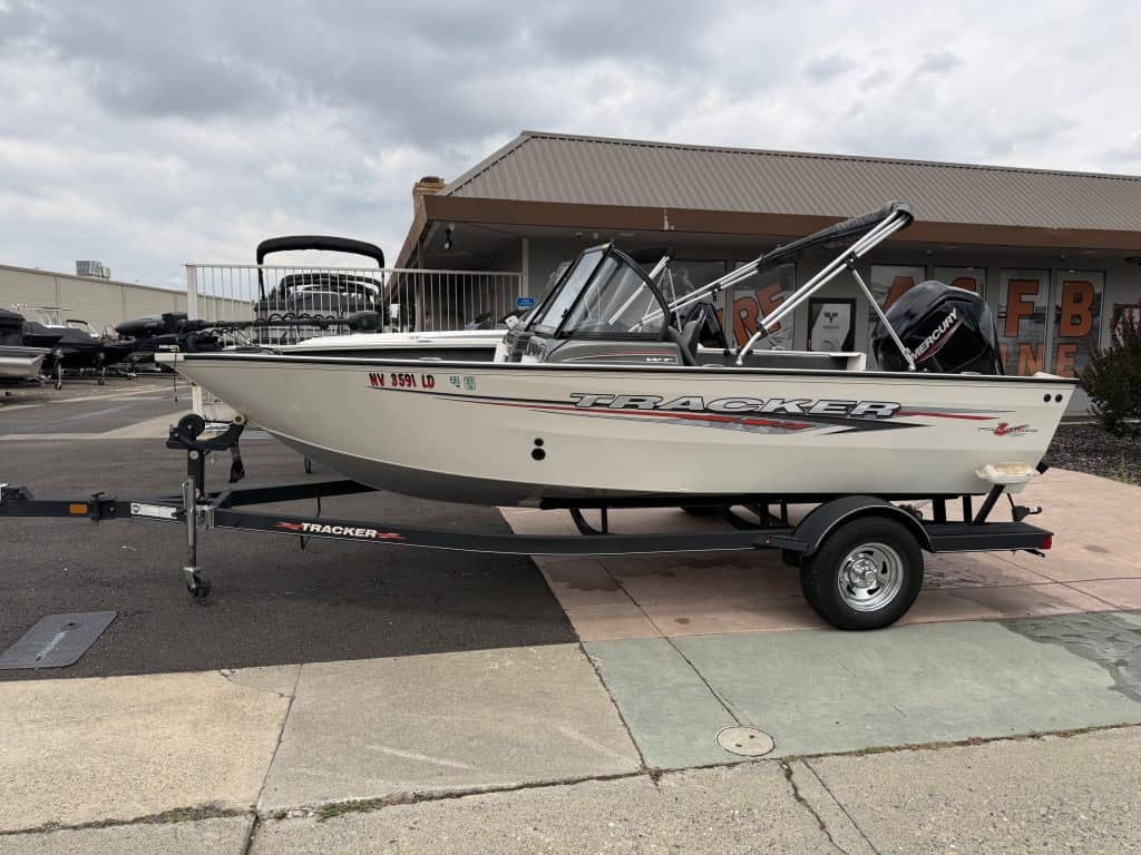 White Tracker fishing boat on trailer with outboard motor, ready for water adventures.