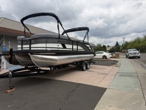 Pontoon boat on trailer ready for sale at marine dealership.