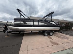 Pontoon boat with black and white design on trailer, ready for water adventures. Perfect for leisure.
