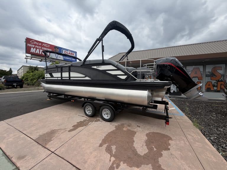 Pontoon boat with outboard engine on trailer, ready for sale or transport.
