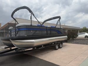 Pontoon boat on trailer ready for transport at marina.