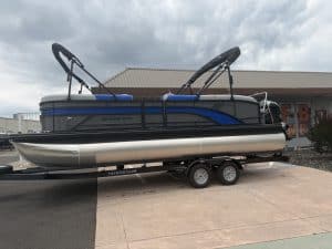 Pontoon boat with water sports gear on trailer, ready for outdoor recreation and boating adventures.
