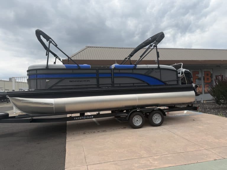 Pontoon boat with water sports gear on trailer, ready for outdoor recreation and boating adventures.