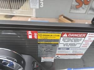Safety and capacity labels on boat with fire extinguisher and warning signs.