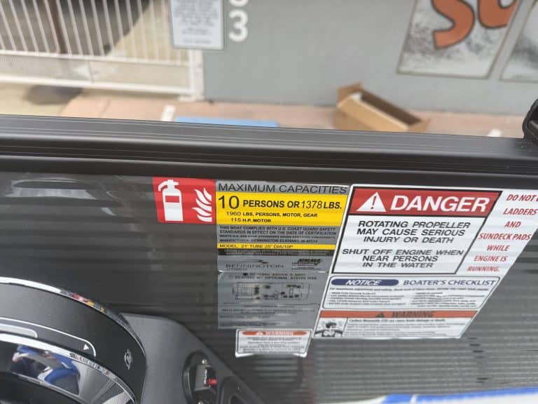 Safety and capacity labels on boat with fire extinguisher and warning signs.