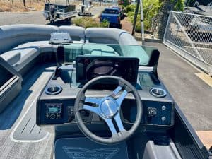 Boat dashboard with steering wheel and navigation screen for marine vessel.