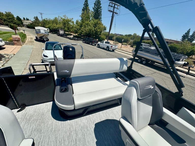 Boat deck with seating area, canopy, and marine equipment at a marina.