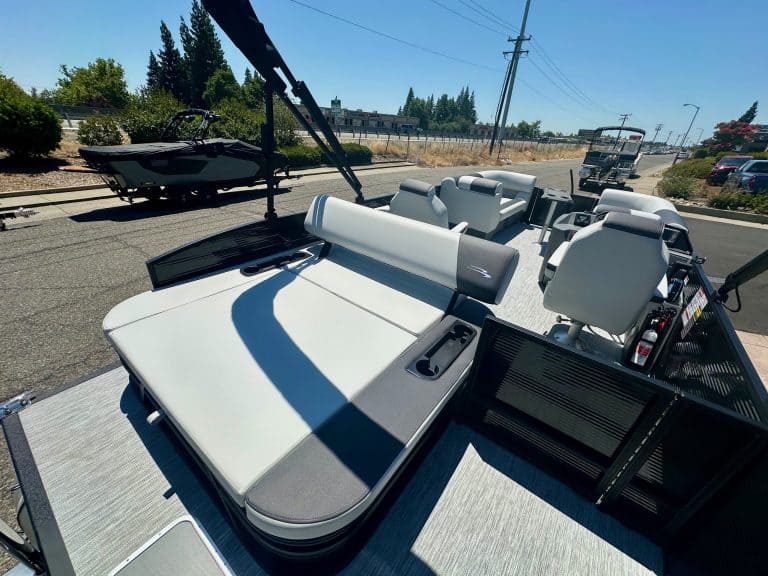 Boat with seating and canopy on trailer for sale at marine dealership.