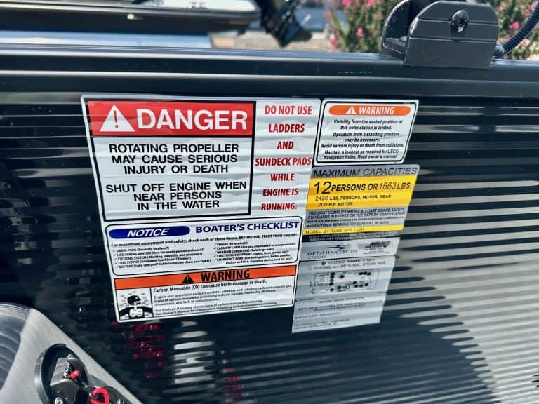 Boat propeller safety warning and maximum capacity labels on marine vessel.