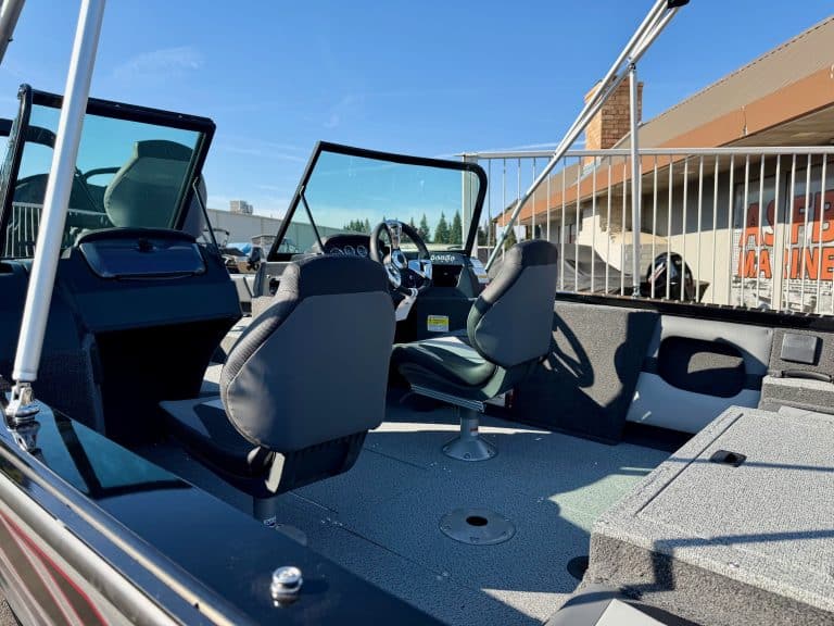 Boat interior with steering wheel, seats, and deck area for leisure activities.