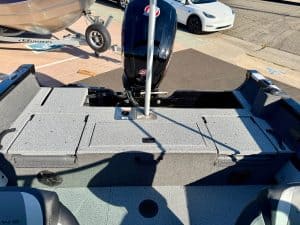 Outboard motor on boat deck with parking lot in the background, showcasing marine vessel features fo.