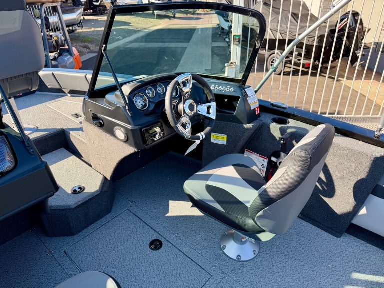 Helm console of a boat featuring steering wheel, gauges, and control panel for optimal navigation.
